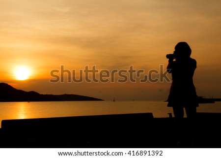 silhouette of woman using the digital camera take photho when sunrise