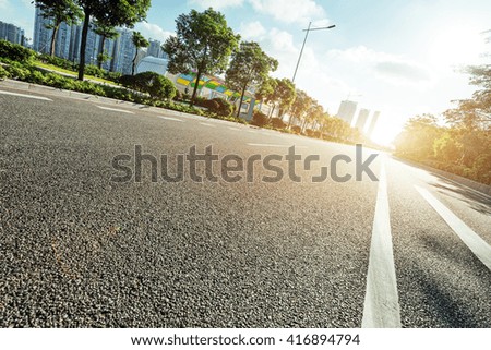 empty asphalt road in modern city at sunrise