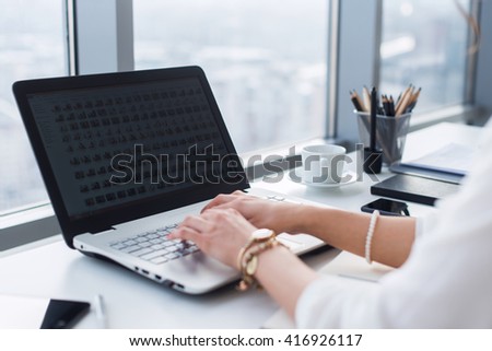 Side view picture of female hands typing, using pc in a light office. Designer working at workplace, searching new ideas.