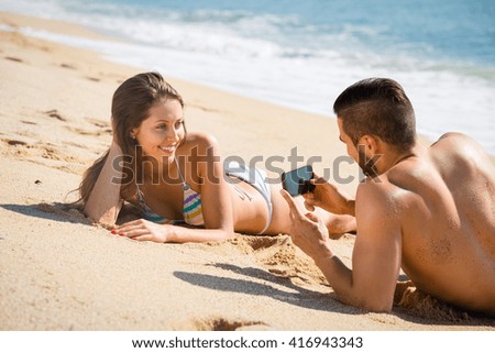 Beautiful woman has asked her boyfriend to take a photo of her lying on a beach