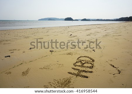 Happy birthday write on sand at beach, beside view.