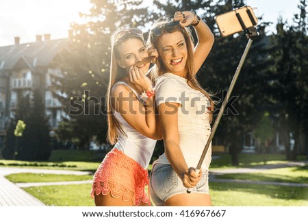 Two attractive women taking a selfie in the city at summer.