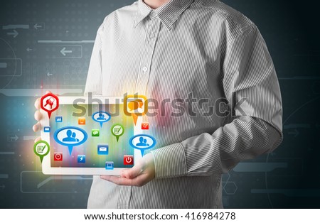 Young businessman presenting modern tablet with colorful social signs and icons
