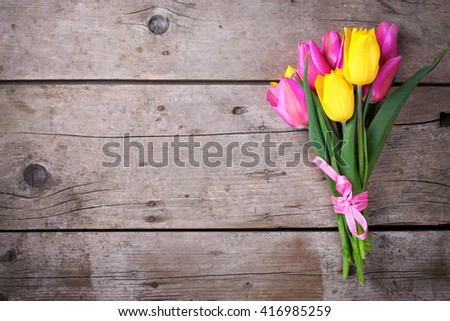Bunch of bright yellow and pink spring tulips on vintage wooden background. Selective focus. Place for text.