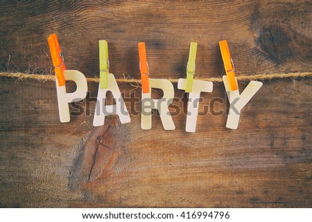 The word PARTY made from wooden letters hanging on the rope over rustic background. retro filtered
