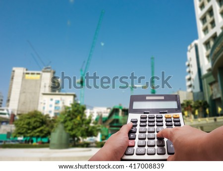 The calculator and building under construction in background , construction cost concept