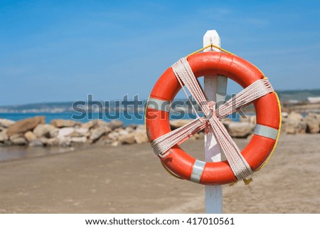 Red lifebuoy ready for safety use close up on empty beach background