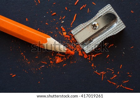 sharpener and orange pencil on black