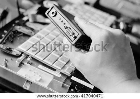 Black and white photography of hands fixing broken computer part, concept of technology