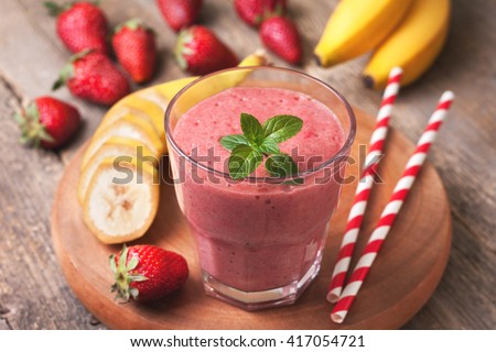 smoothie with banana and strawberry in the glass, fresh strawberries and bananas on the old wooden background Royalty-Free Stock Photo #417054721