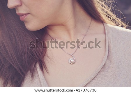 Detal of woman wearing a luxury pearl pendant Royalty-Free Stock Photo #417078730