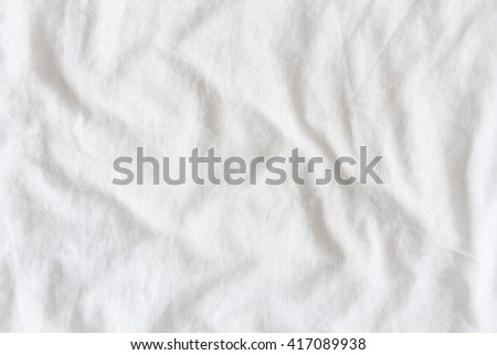 Top view of creased / wrinkles on a white unmade / messy bed sheet after waking up in the morning. Bedsheet is not neatly arranged for new guests or customers to sleep in. Abstract texture background