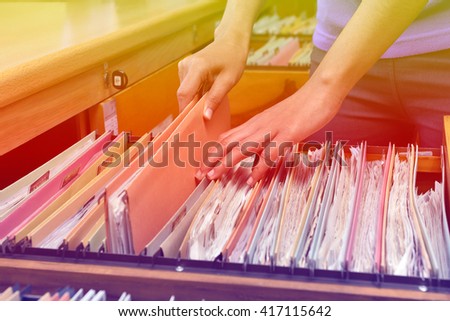 Hand female searching for document in cabinet