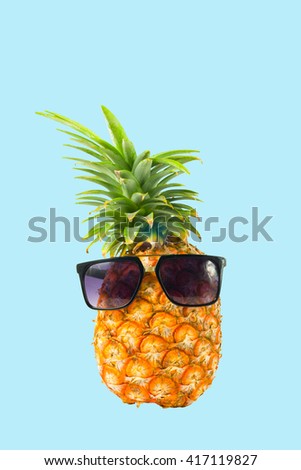 Pineapple wearing sunglasses - Summertime vacation holiday eating healthy concept image on blue background