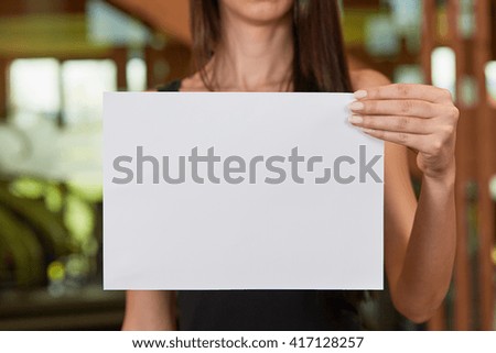 Young caucasian woman holding white sheet of paper
