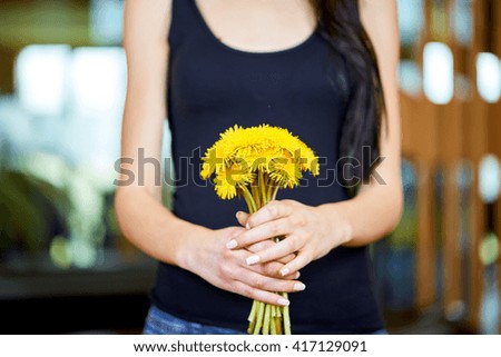 Young caucasian woman holding a bunch of dandelions spring flowers