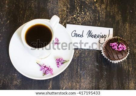Lilac flowers and cup of coffee with good morning note on rustic wooden background