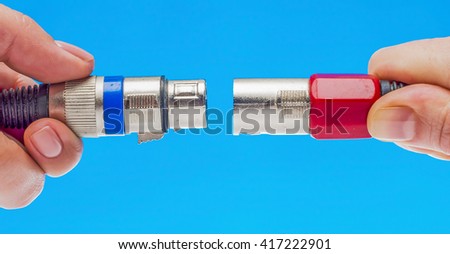 Female hands holding XLR connectors isolated on blue