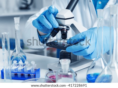 woman in a laboratory microscope with microscope slide in hand.toned image. Royalty-Free Stock Photo #417228691