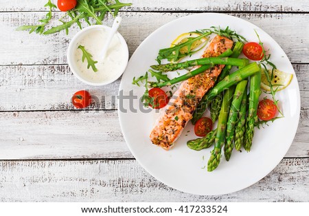 Baked salmon garnished with asparagus and tomatoes with herbs.Top view Royalty-Free Stock Photo #417233524