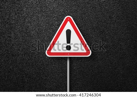 Road sign triangular shape with exclamation mark on a background of asphalt. The texture of the tarmac, top view.