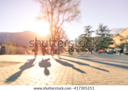 Blurred defocused silhouettes of four people walking on Meran streets at sunset - Wanderlust emotional youth concept with friends traveling together - Warm filter with rose quartz enhanced sunshine