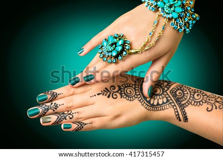 Woman Hands with black mehndi tattoo. Hands of Indian bride girl with black henna tattoos. Hand with perfect turquoise manicure and national Indian jewels. Fashion. India Royalty-Free Stock Photo #417315457