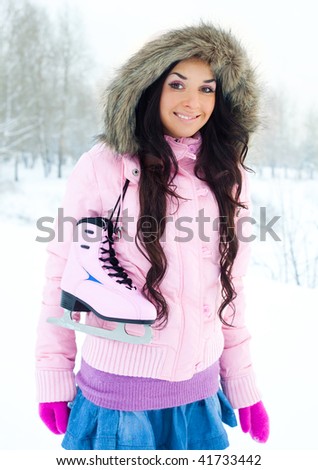 beautiful young brunette woman wearing warm winter clothes going to ice skating
