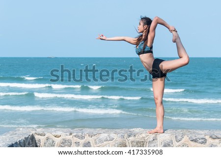 Young woman practicing yoga on the beach.