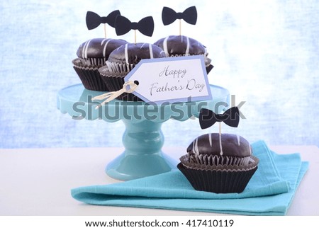 Happy Fathers Day cupcakes on cake stand against a blue background. 