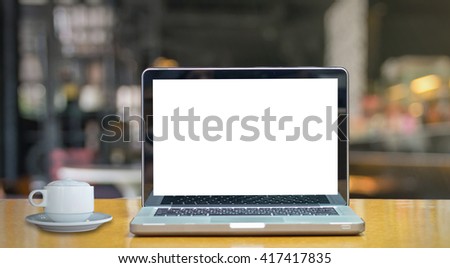 Laptop on the wood table over the coffee shop blurred background