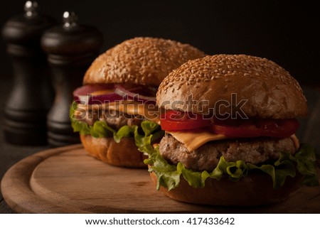 Home made hamburger with beef, onion, tomato, lettuce and cheese. Fresh burger closeup on wooden rustic table with potato fries and chips. 