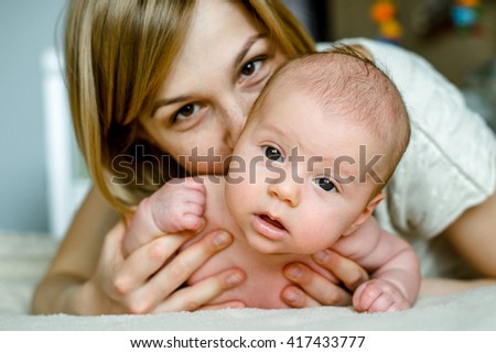 Portrait of happy mother and baby at home. The child is 2 months