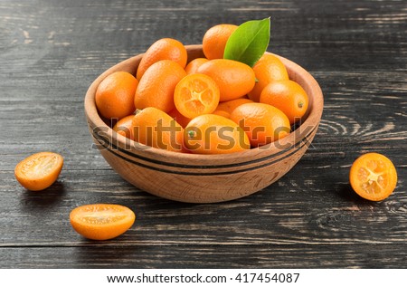 Bowl full of fresh fruit kumquat on the wooden background Royalty-Free Stock Photo #417454087