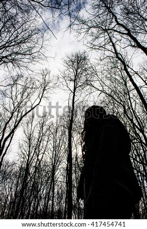 Woman alone in black scary winter forest