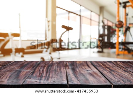 Empty wooden table space platform with fitness gym background. For product display montage.