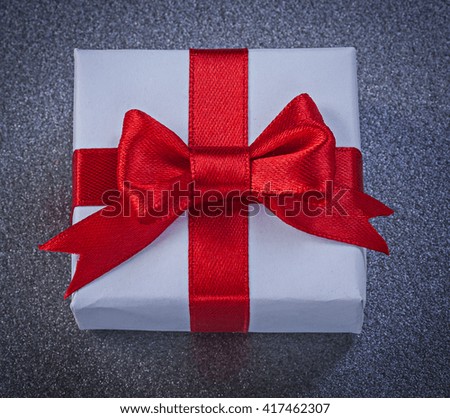 Present box with red tied tape on grey surface top view holidays concept.