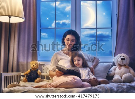 Family reading bedtime. Pretty young mother reading a book to her daughter. Royalty-Free Stock Photo #417479173