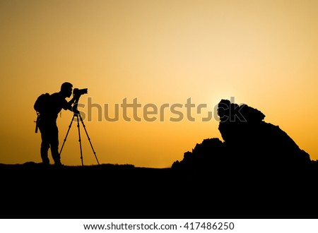 man photographer taking photo on sunset mountain