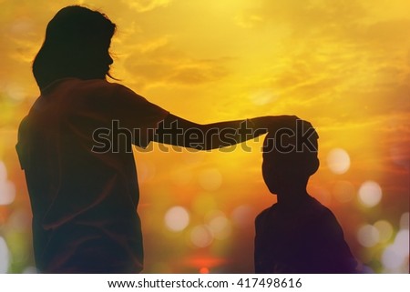Mother and sun silhouettes at sunset with blur nature bokeh background 