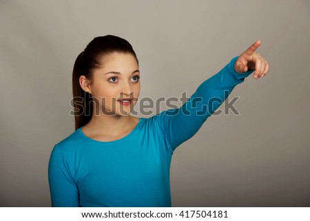 Smiling young woman pointing up.
