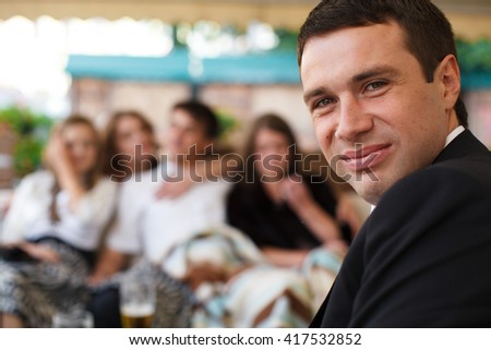 Man smiles over his shoulder surrounded by friends