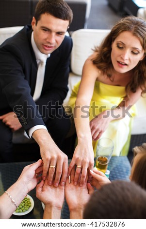 Bride and groom demonstrate their wedding rings to the friends