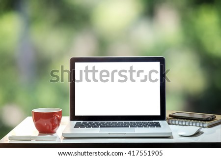 Front view of cup and laptop on table in Office park.blur background