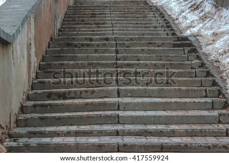 The staircase leading up, in which the people rise or fall. Stairs from the sidewalk stone. Stairs next to dirty snow.