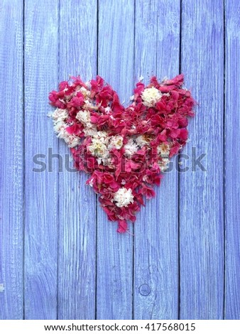 Pink and white petals in heart shape on  wooden background from top view.
Can be used like a vertical card or invitation.