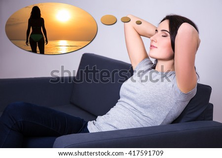 travel concept - young woman lying on sofa at home and dreaming about summer trip