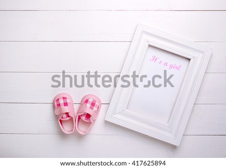 baby's bootees with a frame on a white background