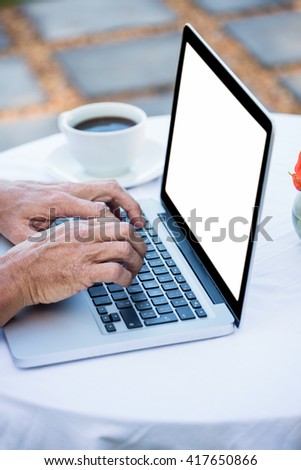 Masculine hands typing on a laptop on a terrace