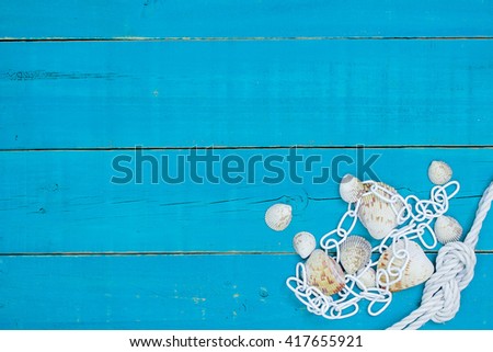 Collection of seashells, chain and rope border on antique rustic teal blue wood background